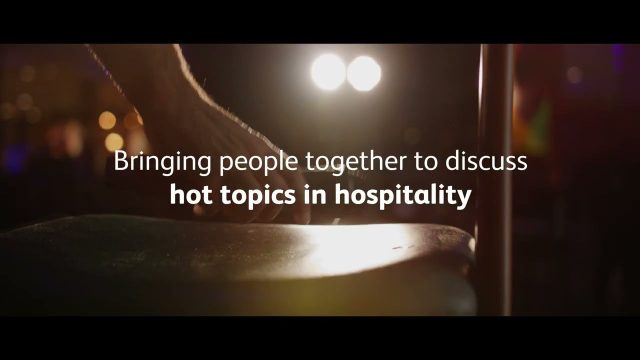 Close-up of a hand touching a stool with the text "Bringing people together to discuss hot topics in hospitality" overlayed on the image.